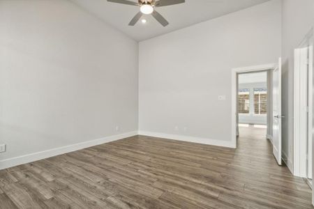 Empty room with high vaulted ceiling, ceiling fan, and dark hardwood / wood-style floors