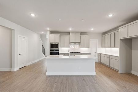 Kitchen featuring stainless steel appliances, light hardwood / wood-style floors, and a center island with sink