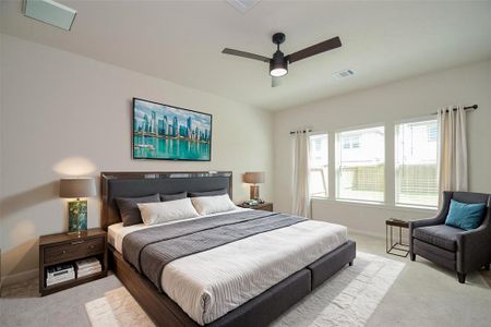 The spacious primary bedroom features large windows, soft carpeting, and a modern ceiling fan for comfort. Natural light fills the room, creating a serene and relaxing atmosphere, making it a perfect retreat at the end of the day.