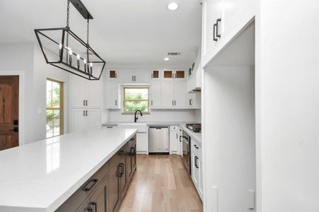 The kitchen also features a large island, a farmhouse-style sink with apron, plenty of beautiful, soft-close cabinetry and an abundance of quartz countertop space!