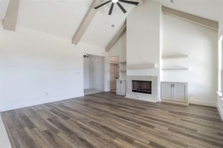 Unfurnished living room with high vaulted ceiling, a high end fireplace, ceiling fan, and dark wood-type flooring