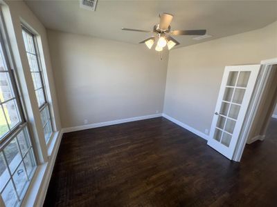 Spare room with dark wood-type flooring, ceiling fan, and a wealth of natural light