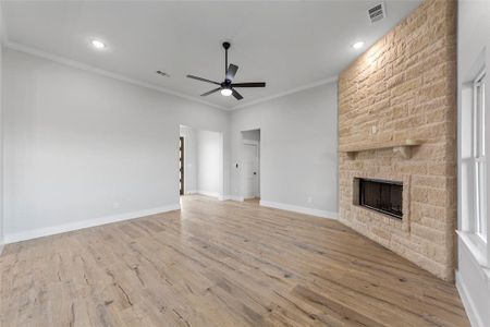 Unfurnished living room featuring a fireplace, ceiling fan, light wood-type flooring, and crown molding