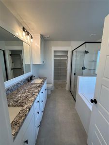 Full bathroom with dual vanity, toilet, tile patterned floors, and separate shower and tub
