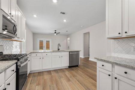 In this kitchen, white cabinets exude a sense of freshness and purity, perfectly paired with the luminous beauty of granite countertops. The open layout fosters a welcoming atmosphere, inviting conversation and interaction between the kitchen and living area.