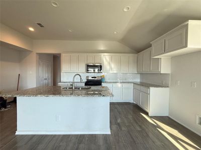 Kitchen featuring an island with sink, sink, white cabinets, and stainless steel appliances