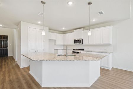 Kitchen with white cabinets, hardwood / wood-style floors, and a kitchen island with sink