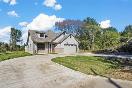 View of front of home featuring a front lawn, a garage, and covered porch