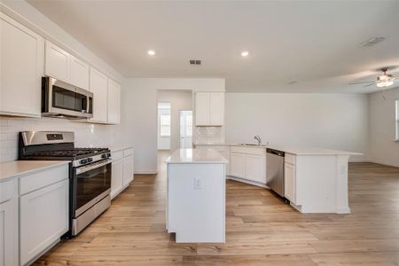 Kitchen featuring light hardwood / wood-style flooring, a kitchen island, stainless steel appliances, backsplash, and ceiling fan