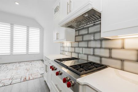 Kitchen featuring light hardwood / wood-style flooring, white cabinets, tasteful backsplash, and stove