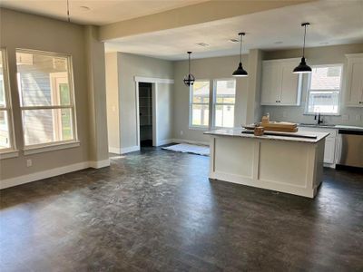 Kitchen featuring stainless steel dishwasher, white cabinetry, decorative light fixtures, and plenty of natural light