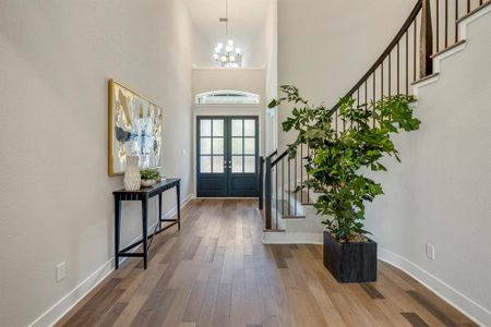 This beautifully designed entryway features high ceilings, elegant hardwood floors, and a curved staircase.