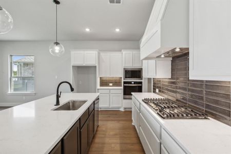 Kitchen featuring hanging light fixtures, appliances with stainless steel finishes, dark hardwood / wood-style flooring, white cabinetry, and sink