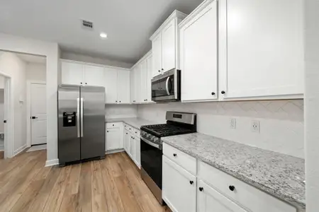 The kitchen features pristine white cabinets that create a timeless aesthetic, complemented by the elegance of complementing granite countertops.