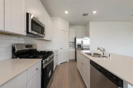 Kitchen featuring white cabinets, light hardwood / wood-style floors, appliances with stainless steel finishes, and sink