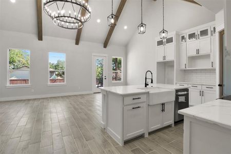 Kitchen with white cabinetry, sink, beamed ceiling, and decorative light fixtures