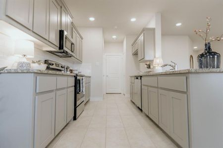 Kitchen with light stone countertops, stainless steel appliances, backsplash, and light tile patterned floors