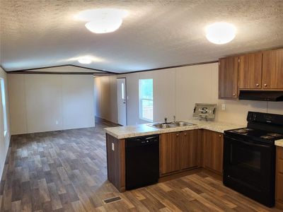 Kitchen featuring dark wood-type flooring, black appliances, a textured ceiling, and vaulted ceiling