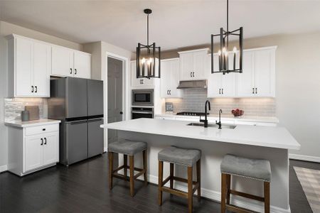 This light and bright kitchen features a large quartz island, white cabinets, a large sink overlooking your family room, recessed lighting with additional pendant lighting, and beautiful backsplash.