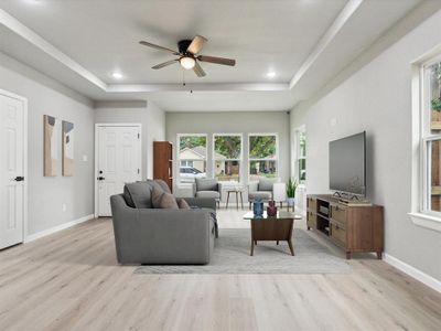 Living room featuring light wood-type flooring, a tray ceiling, and ceiling fan