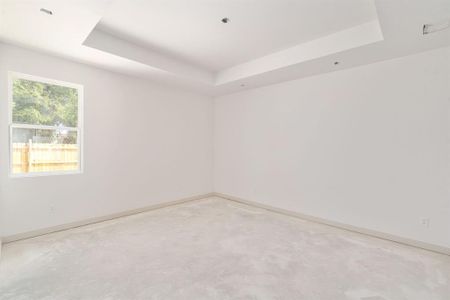 Empty room featuring concrete floors and a raised ceiling