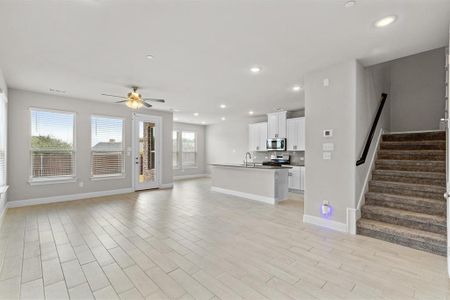 Unfurnished living room with a wealth of natural light, ceiling fan, and light hardwood / wood-style floors