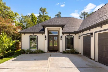 Gorgeous stucco and brick exterior with dark garage doors make for a captivating appearance.