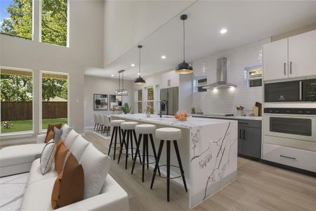 Kitchen with white cabinets, oven, hanging light fixtures, and wall chimney range hood