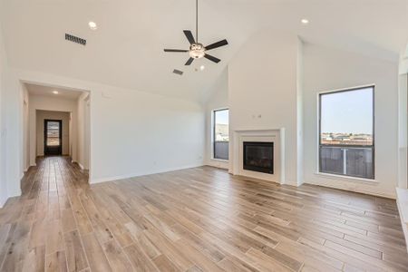 Unfurnished living room featuring ceiling fan, high vaulted ceiling, and light wood-type flooring