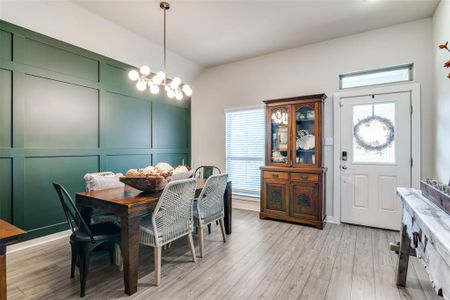 Dining space featuring a notable chandelier, lofted ceiling, and light hardwood / wood-style floors