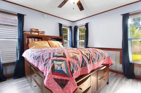 Bedroom featuring light hardwood / wood-style flooring, ceiling fan, and crown molding