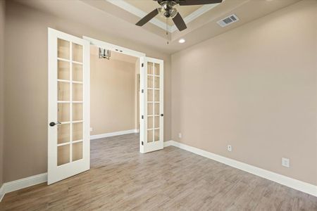 Unfurnished room featuring french doors, a tray ceiling, light hardwood / wood-style floors, ceiling fan, and crown molding