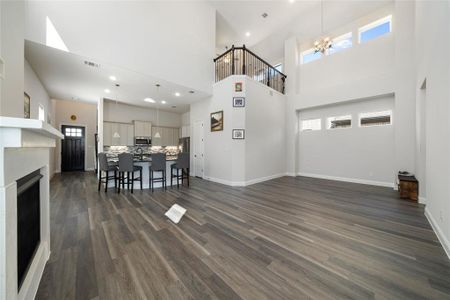 Living room featuring a wealth of natural light, dark wood-type flooring, a towering ceiling, and an inviting chandelier