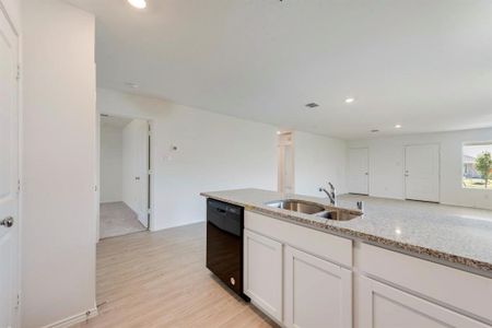 Kitchen featuring white cabinetry, sink, black dishwasher, light stone counters, and light hardwood / wood-style floors