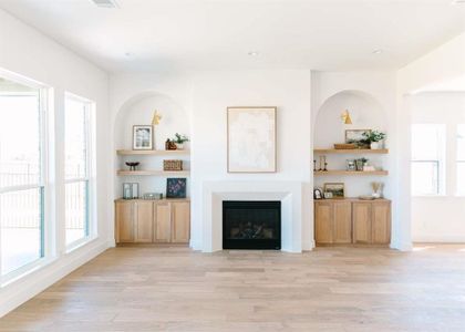 Unfurnished living room featuring a wealth of natural light, light hardwood / wood-style floors, and built in features