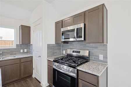 Kitchen with lofted ceiling, decorative backsplash, appliances with stainless steel finishes, and dark hardwood / wood-style flooring