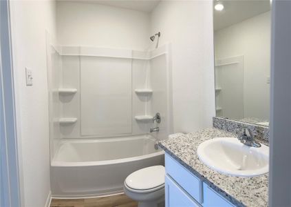 Primary bathroom includes granite counters, designer white cabinetry and luxury vinyl plank flooring.