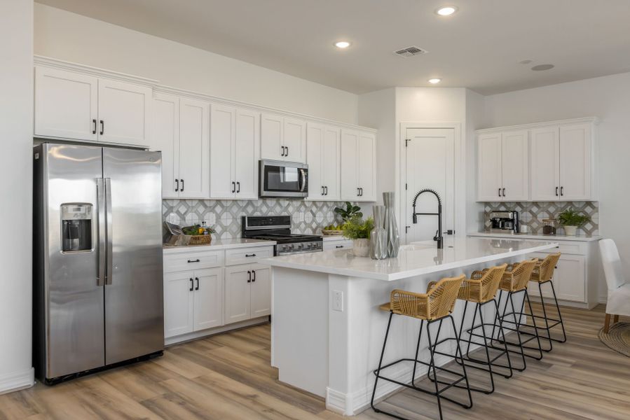 Jimson Kitchen. Stainless steel appliances, white cabinets and white counter tops. Wood Floor. Bamboo bar stools new home construction by William Ryan Homes Phoenix