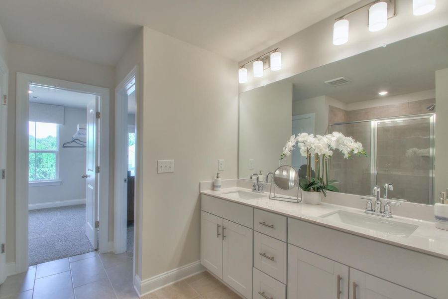 The primary bathroom offers a large walk-in shower and dual vanity sinks.