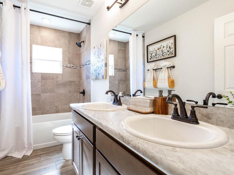 A dual vanity hall bath serves the secondary bedrooms and guests in your home - Serendipity model home in Zephyrhills
