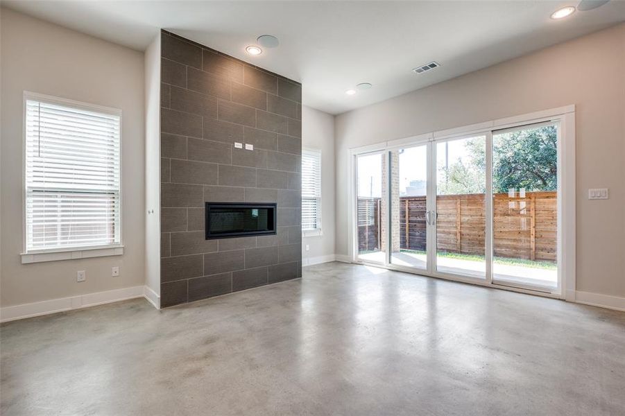 Unfurnished living room featuring plenty of natural light and a tile fireplace