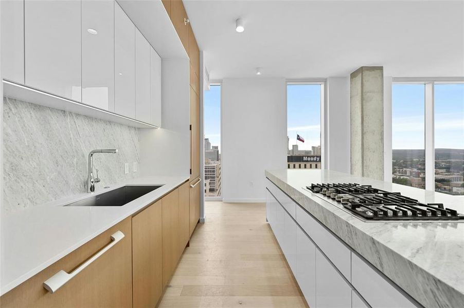 This contemporary kitchen seamlessly blends style and functionality, featuring modern light wood cabinetry, polished marble countertops, and top-of-the-line stainless steel appliances. The expansive kitchen island offers ample space for meal prep or casual dining, making it the heart of the home. *Linden Residence No. 2105 Shown Here