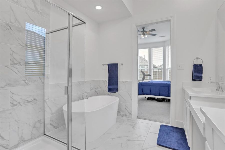 Bathroom featuring tile walls, tile patterned floors, separate shower and tub, vanity, and ceiling fan