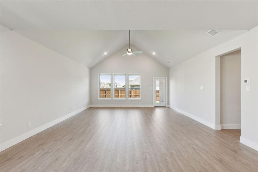 Unfurnished living room with lofted ceiling, ceiling fan, and light hardwood / wood-style floors