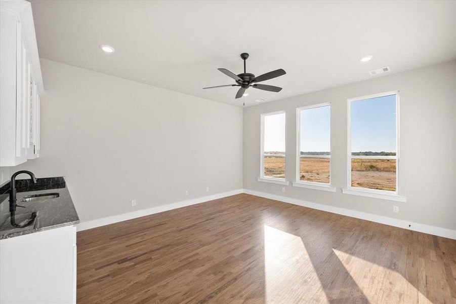 Unfurnished living room with sink, wood-type flooring, and ceiling fan