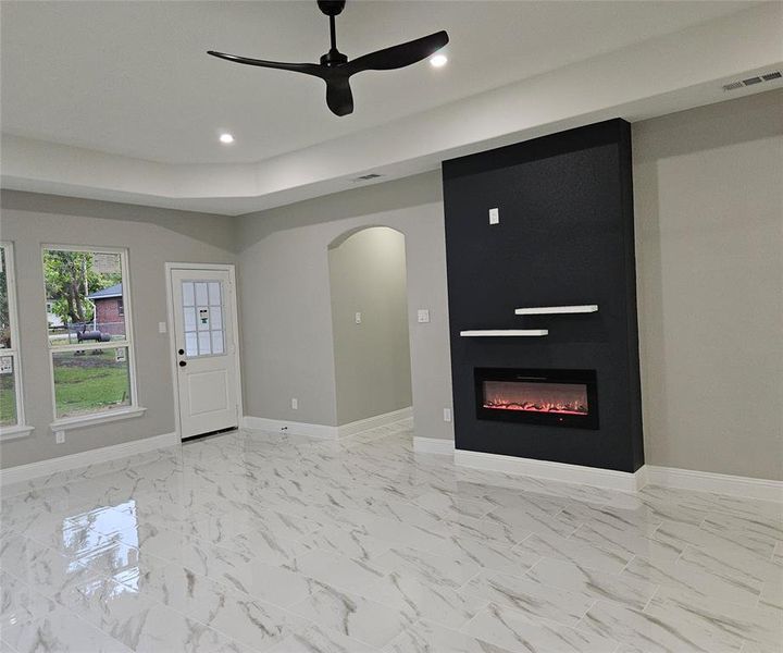 Open living room featuring ceiling fan and a large fireplace