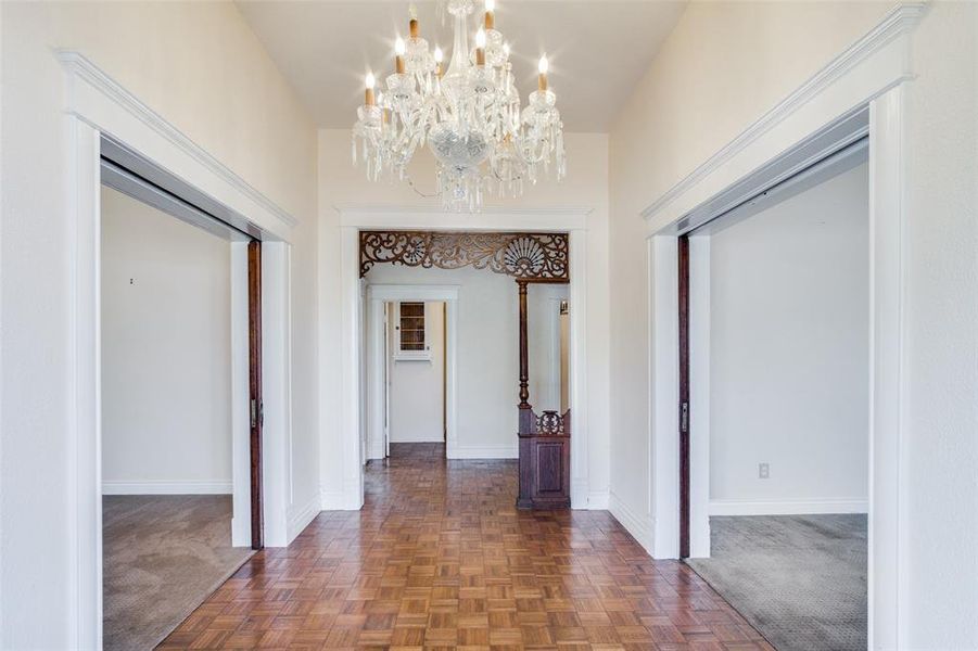 Hallway with a notable chandelier and dark parquet floors