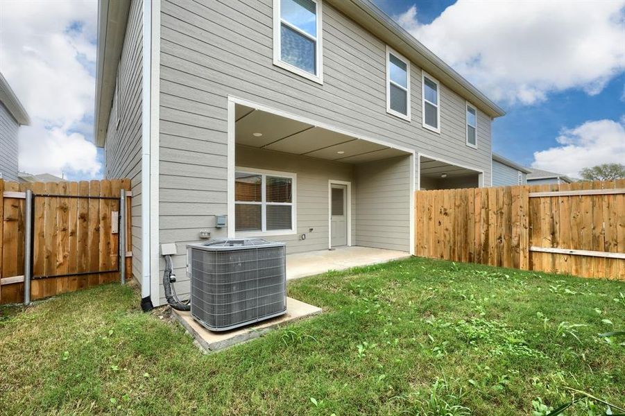 Rear view of house with central air condition unit, a patio area, and a lawn