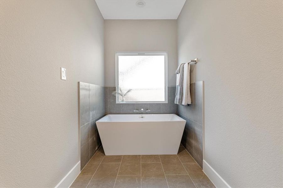 Bathroom featuring tile patterned floors, a bathtub, and tile walls