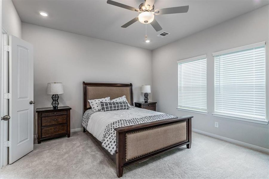 The serene primary bedroom offers a tranquil retreat with its soft carpeting, modern ceiling fan, and large windows that fill the room with natural light. Spacious enough for a king-size bed and additional furniture, it provides the perfect place to unwind after a long day. **This image is from another Saratoga Home - Mockingbird floorplan.**